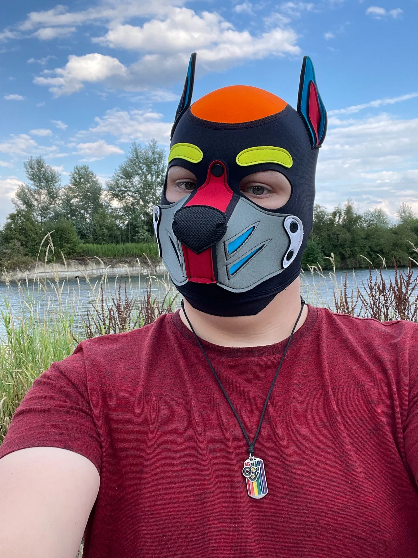 PHØENIX mit Puppy-Maske draußen am Wasser unter blauem Himmel